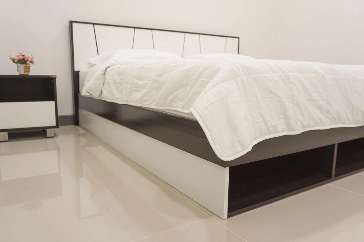 A low-frame mobility bed near the floor with a bed side table