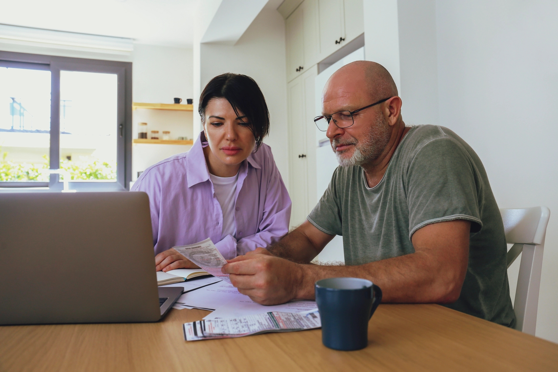 A couple viewing their monthly bills or documents in front of a laptop