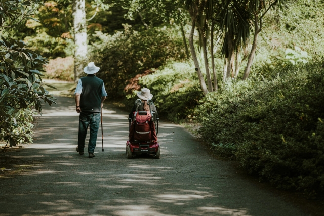 An elderly couple on mobility scooter in greenery