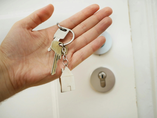 Person holding keys to new home in palm of hand.