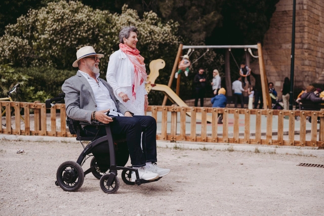 Elderly couple in park using mobility chair