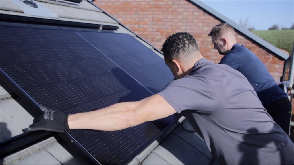 Two men installing solar panels on rooftop