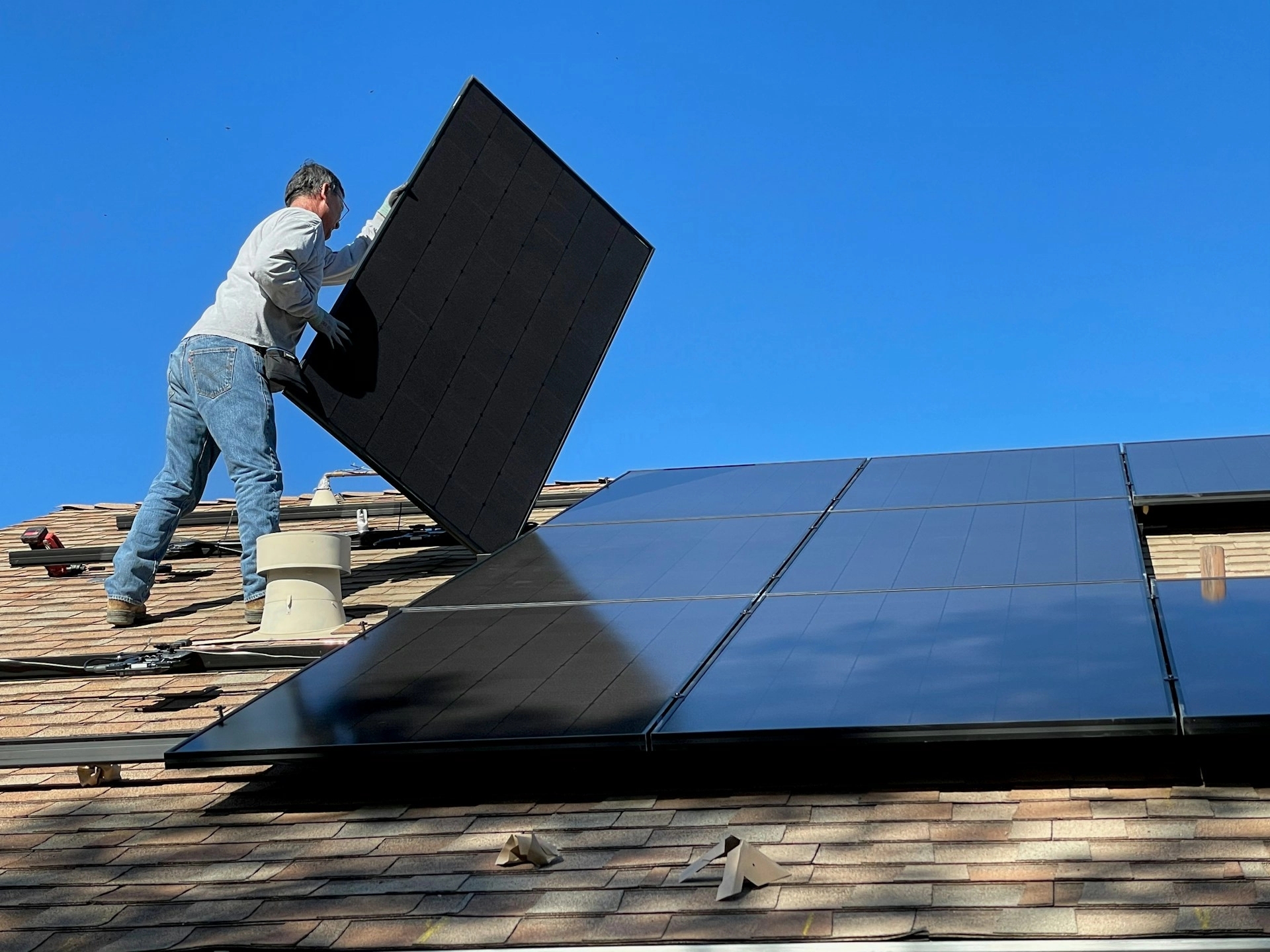 Man fitting a solar panel on roof